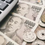 Notas e moedas de ienes japoneses com calculadora, destacando a isenção de imposto de residência