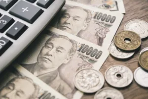 Notas e moedas de ienes japoneses com calculadora, destacando a isenção de imposto de residência