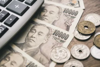 Notas e moedas de ienes japoneses com calculadora, destacando a isenção de imposto de residência