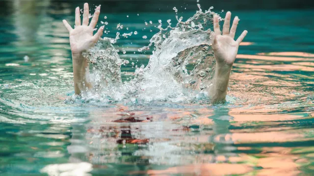 Criança segura em piscina, prevenindo afogamento infantil